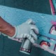 Osoba w rękawiczkach trzyma puszkę farby w sprayu