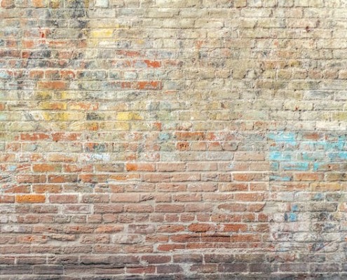 ściana z cegły z nie do końca wyczyszczonym graffiti